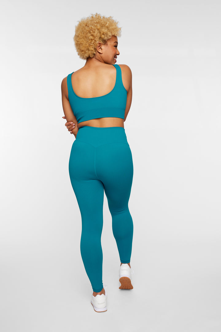 Back view of woman in petrol green ribbed seamless leggings showing sculpted fit and support