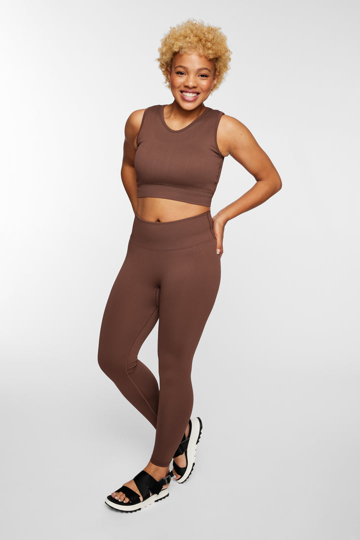 Woman wearing espresso ribbed seamless leggings – front full view, styled with longline sports bra