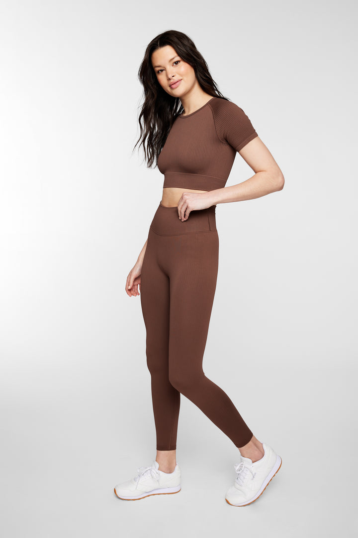Woman wearing espresso ribbed seamless leggings – front full view, styled with sports bra