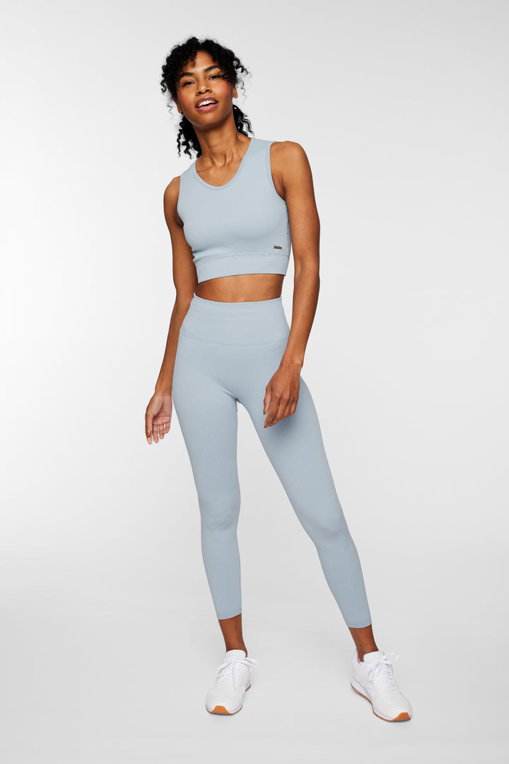 Woman wearing aqua ribbed seamless leggings – front full view, styled with sports bra